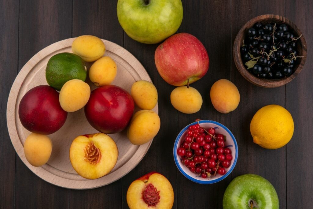 top view peaches stand with apricots apples red black currants wooden surface